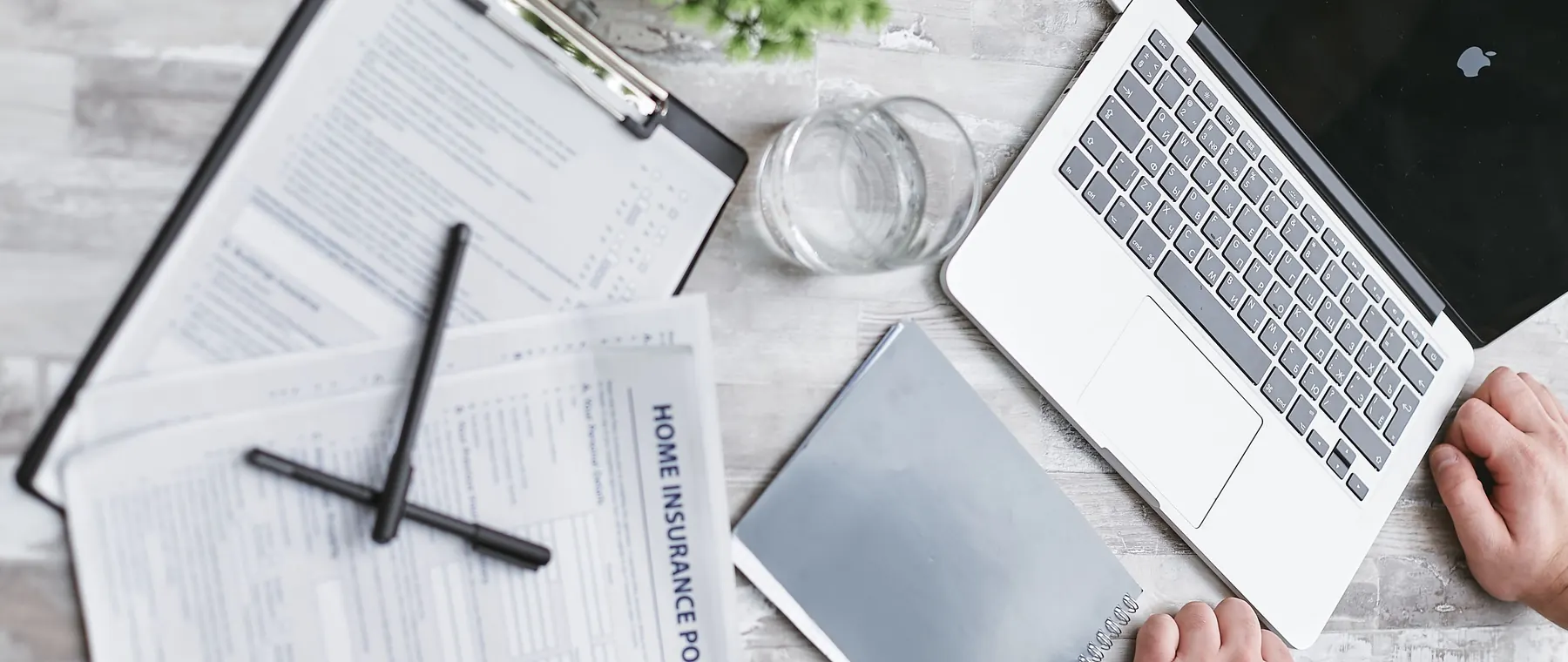 Top view of home insurance forms, laptop, and documents on a desk, conveying a professional office setting.