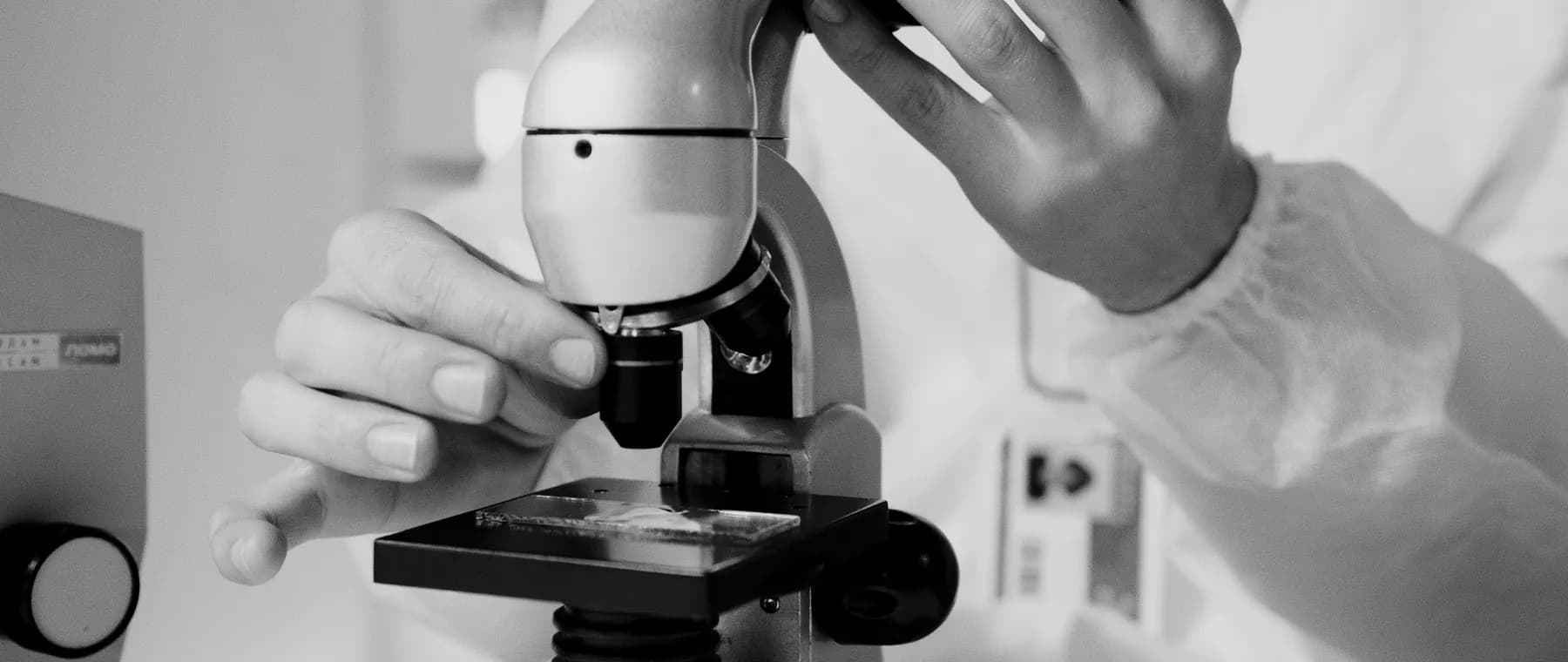 A scientist in a lab coat using a microscope for research in a laboratory setting.