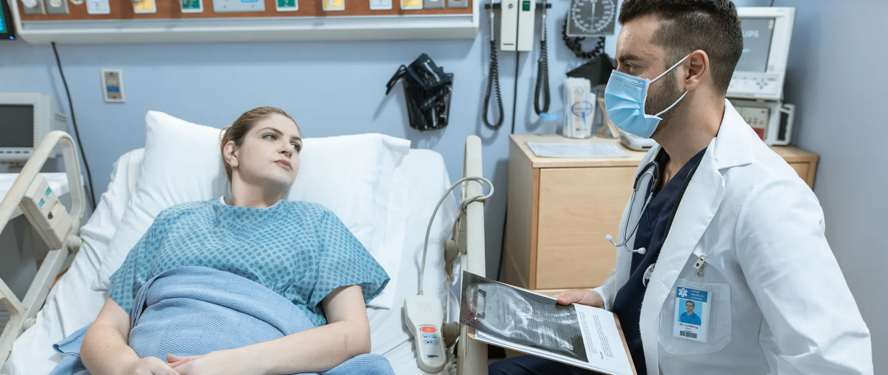 A medical practitioner discusses health details with a patient in a hospital setting.