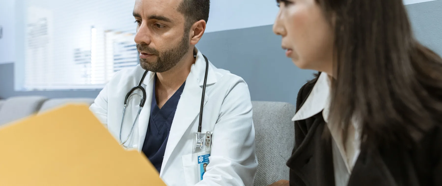 A physician going through a patient file with them at a first visit