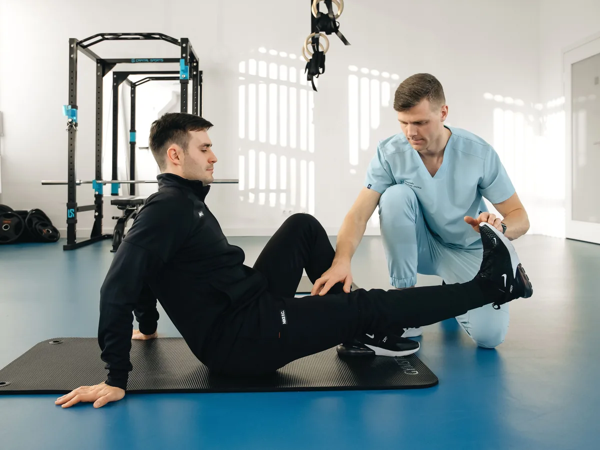 A physiotherapist assists a male patient during a rehabilitation session in a modern clinic.