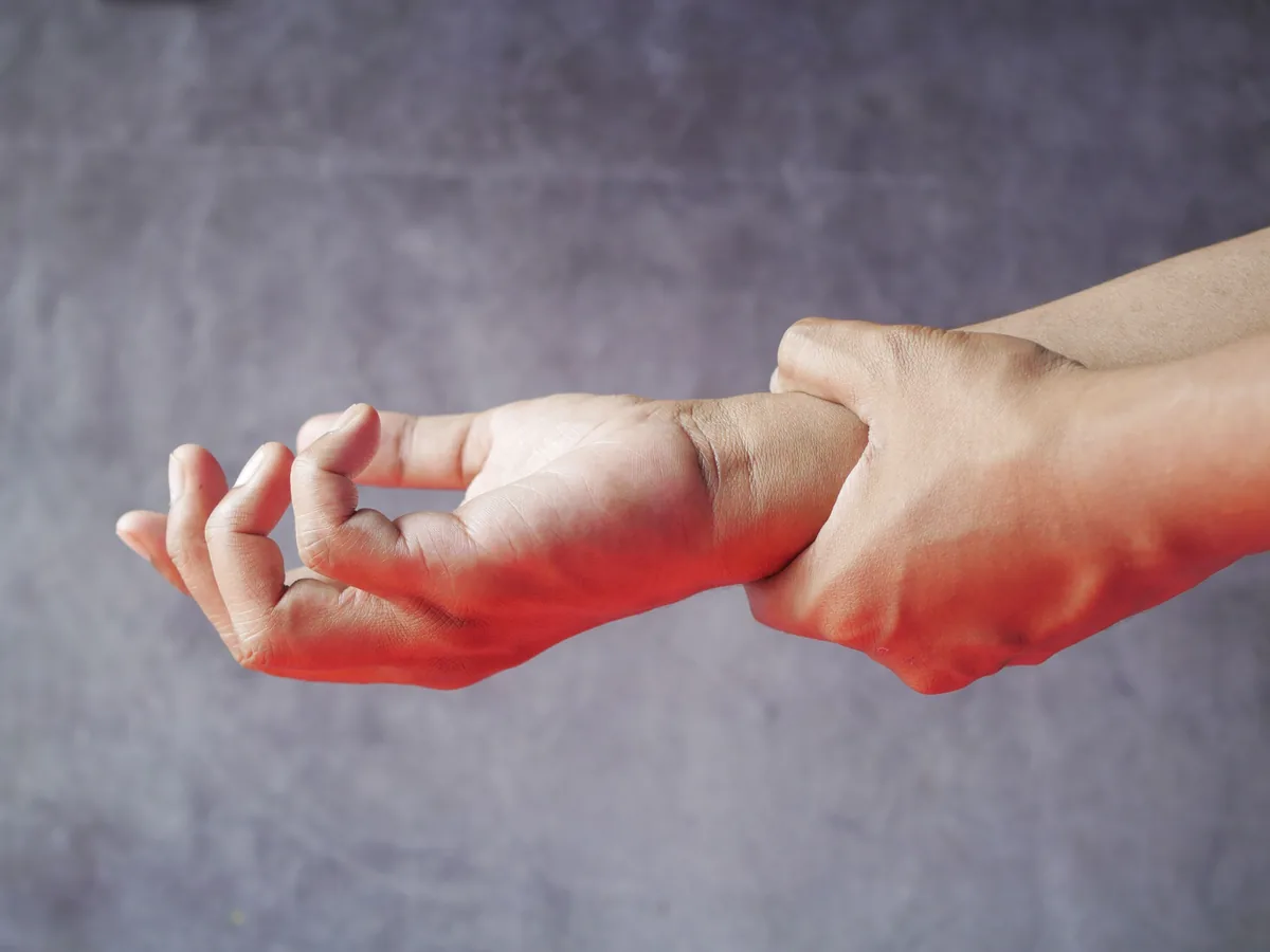 Close-up of hands, one grasping the other, symbolizing pain or discomfort.