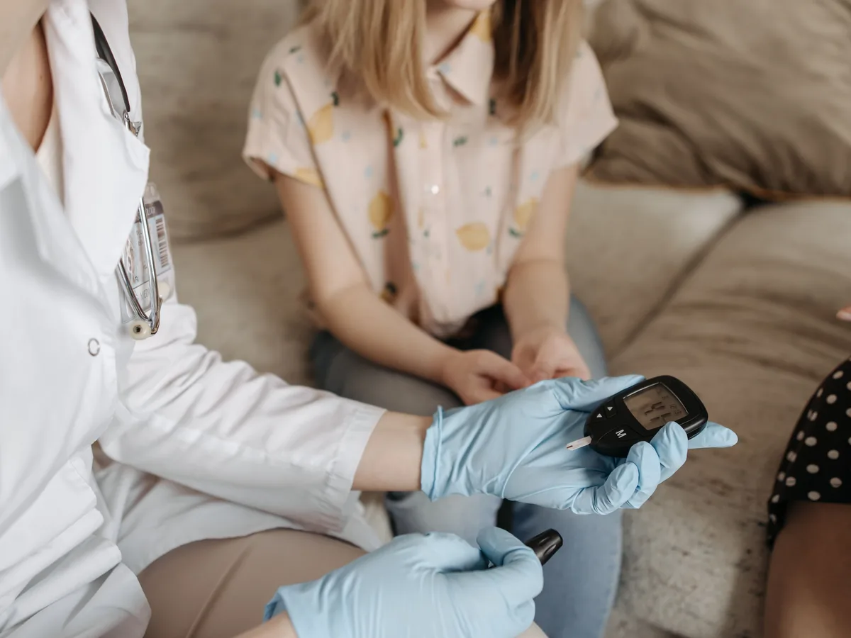 Doctor using a glucose meter to check a patient's blood sugar during a medical consultation.