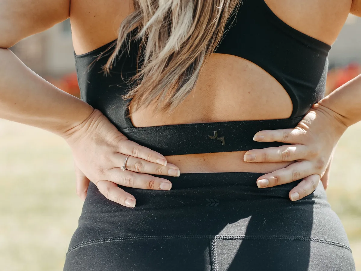 A woman pressing a hand to her lower back where the sacroiliac joint sits