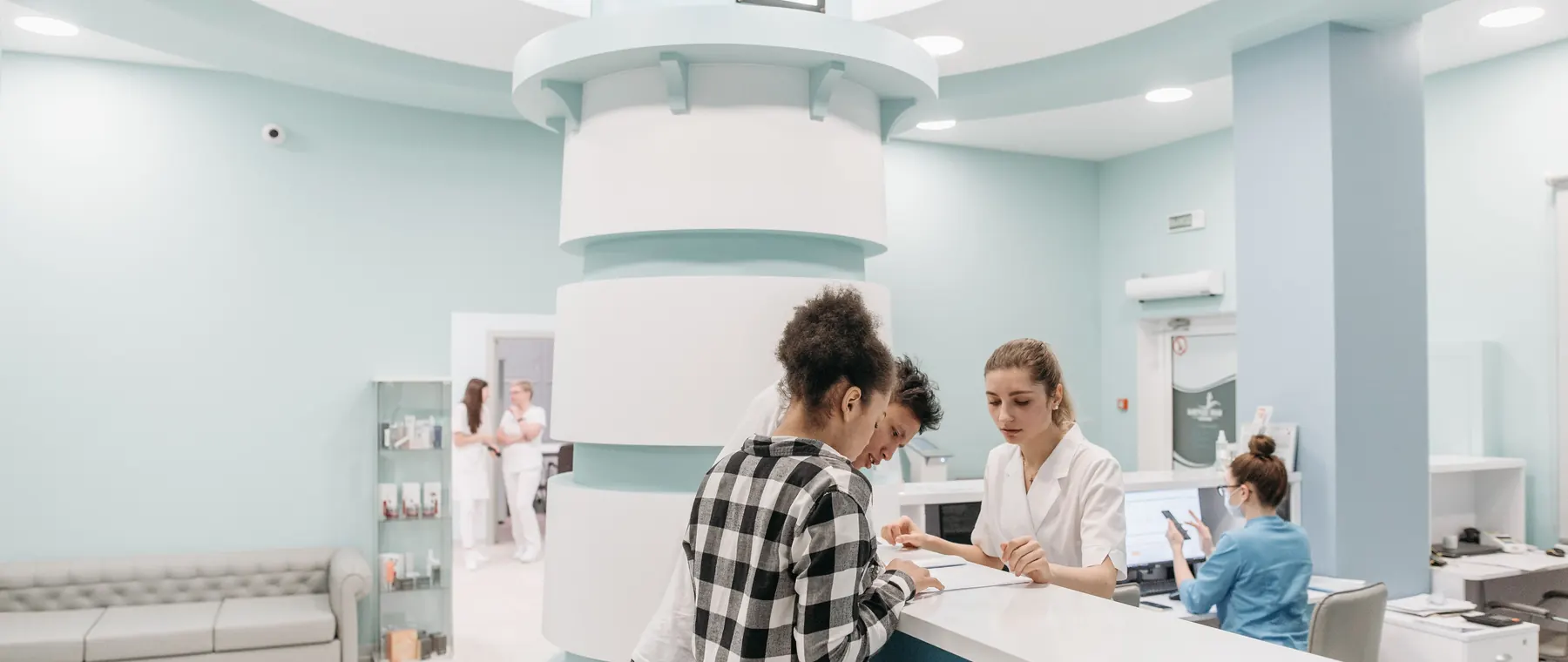 Bright, welcoming clinic reception with patients interacting with staff for registration.