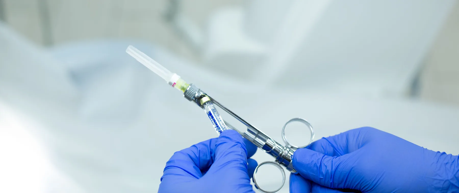 Gloved hands drawing up a sterile syringe before an injection