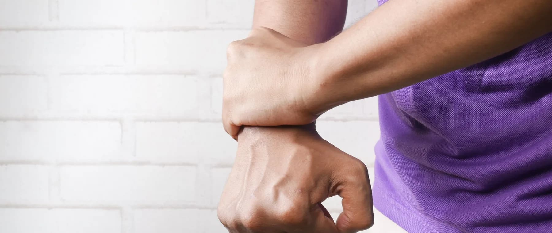 A person gripping their own forearm, as people do with limb pain
