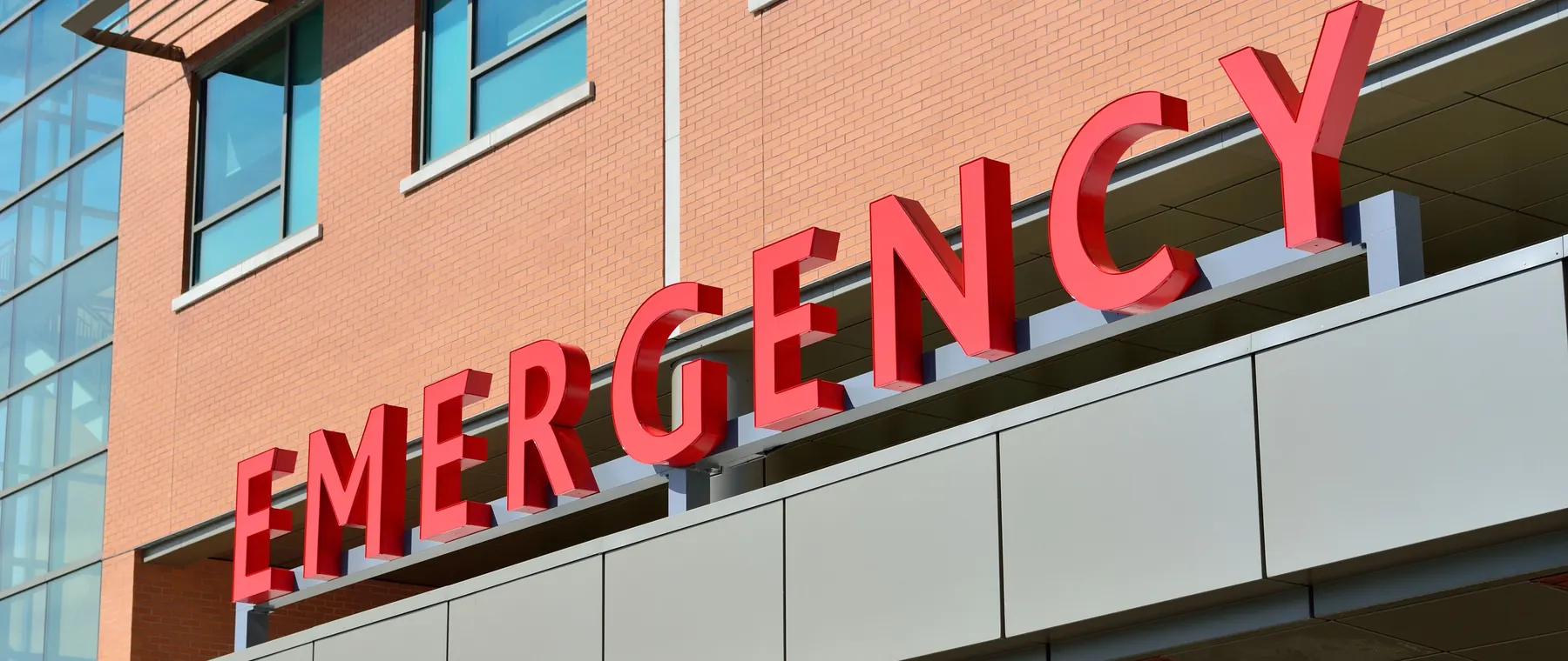 Close-up of a modern hospital emergency room entrance with prominent red letters.